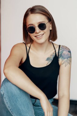 Kırmızı duvarın yanındaki beyaz sandalyede oturan genç kız