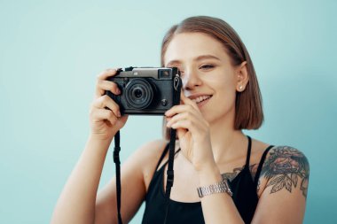 Genç kız fotoğrafçı mavi arka plan üzerinde fotoğraf çekmek