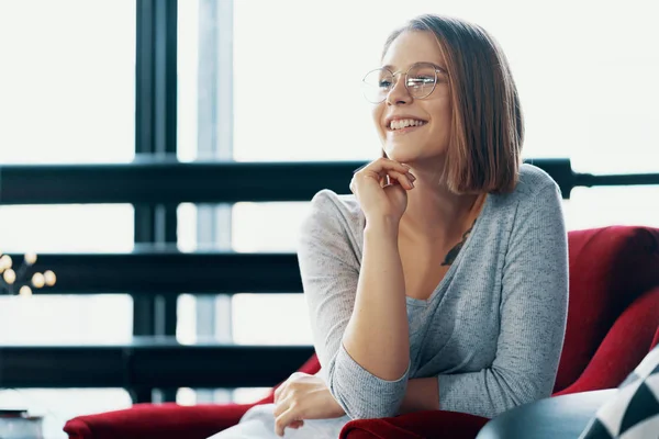 Attraktive Mädchen sitzt in einem roten gemütlichen Stuhl — Stockfoto