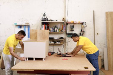 Marangozlar atölyede dizüstü bilgisayar kullanarak çözüm arıyorlar.