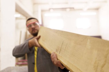 Erkek marangoz atölyesinde ahşapla çalışıyor.