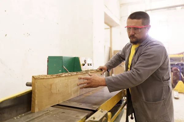 Mannelijke timmerman met zaag voor het zagen van hout in de werkplaats — Stockfoto