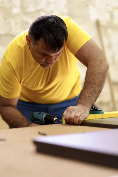 De timmerman maakt gaten om meubels te monteren met behulp van apparatuur — Stockfoto