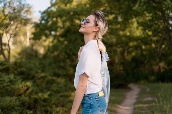 Donna con gli occhiali da sole che cammina nel parco — Foto Stock