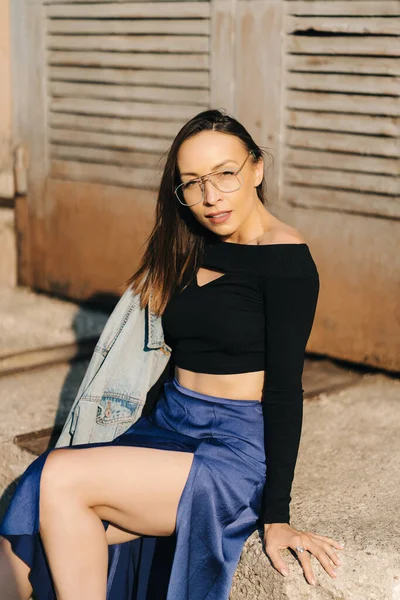 Jolie jeune femme brune portant un haut noir et des lunettes transparentes posant dans la rue — Photo