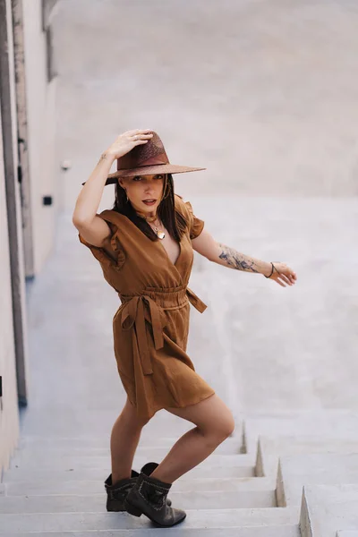 Jong mode meisje gekleed in een zomer jurk met een rieten brede hoed loopt en poseert in de oude stad — Stockfoto