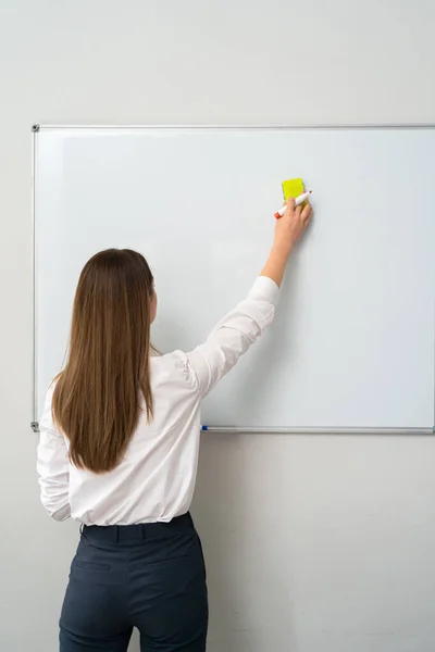 Young woman writing on a whiteboard in an office, — Stock Photo, Image