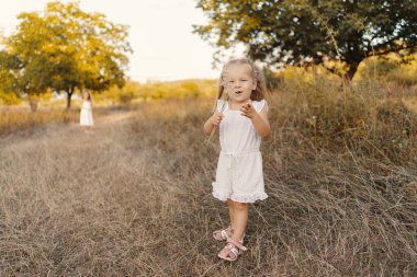 Güzel kız kardeşler doğada tatil yaparken oyun oynuyorlar.