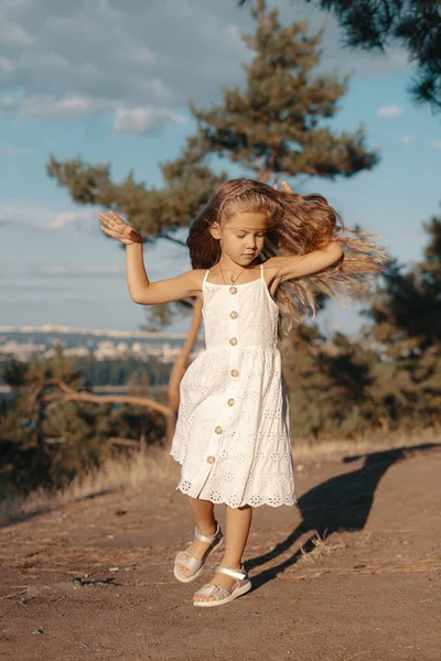 Klein meisje met golvend haar spelen terwijl rusten in de natuur — Stockfoto