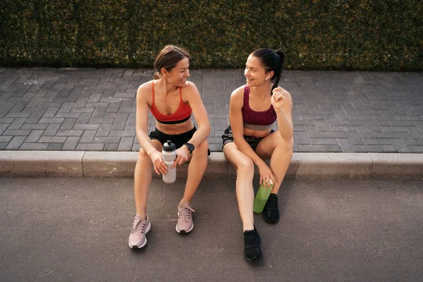 两名年轻美丽的女运动员在城市锻炼后休息的画像 — 图库照片