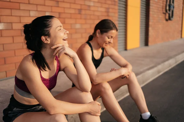 两名年轻美丽的女运动员在城市锻炼后休息的画像 — 图库照片