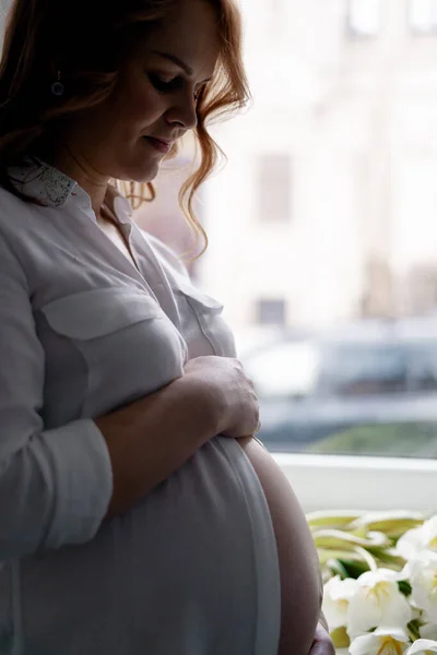 Femme enceinte avec des tulipes blanches à la maison — Photo