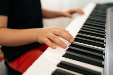 Okul çocuğu elleri evde sentezleyici oynuyor.