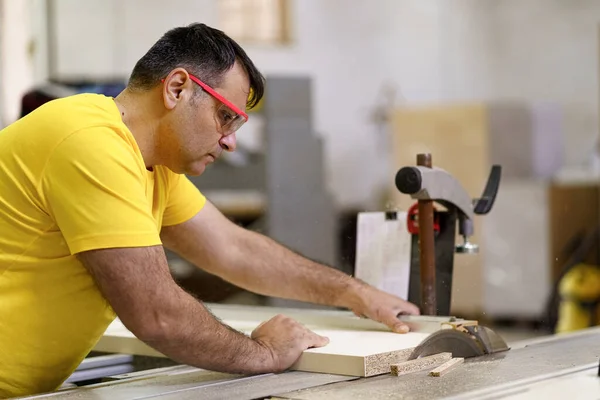 Mannelijke timmerman met zaag voor het zagen van hout in de werkplaats — Stockfoto