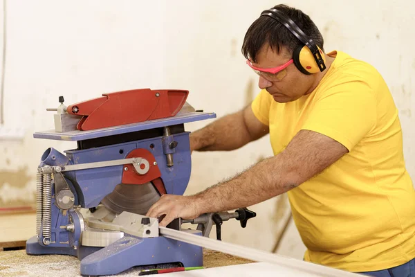 Mannelijke timmerman met zaag voor het zagen van hout in de werkplaats — Stockfoto