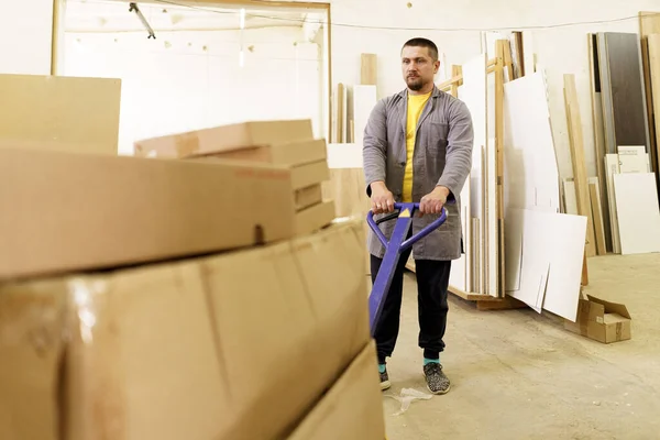 Homem transportar caixas de papelão móveis em sua oficina — Fotografia de Stock