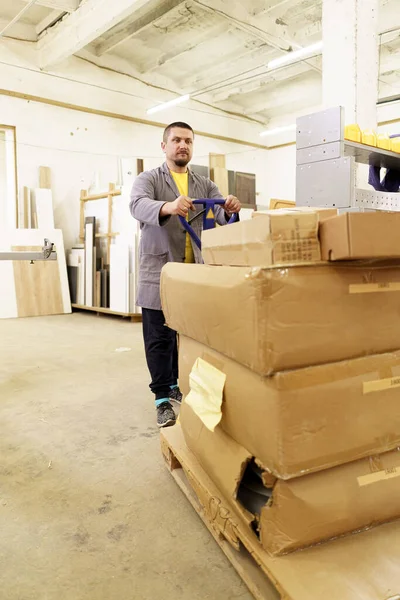 Homem transportar caixas de papelão móveis em sua oficina — Fotografia de Stock