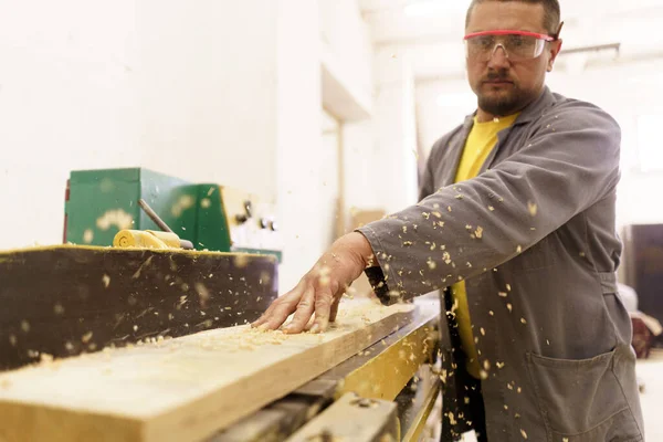 Mannelijke timmerman met zaag voor het zagen van hout in de werkplaats — Stockfoto