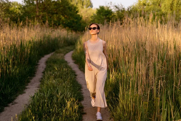 Ifjú hölgy sétál az erdőben egy napsütéses napon. — Stock Fotó
