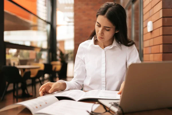 Mulher bonita em óculos falando usando laptop com sorriso enquanto sentado e trabalhando — Fotografia de Stock