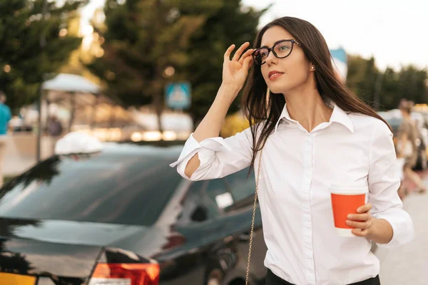 Joven empresaria cogiendo un taxi con un café para llevar —  Fotos de Stock