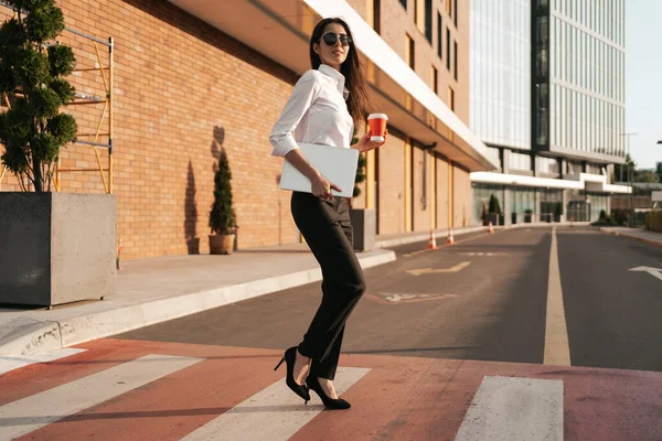 Mulher de camisa branca segurando um café para atravessar a rua — Fotografia de Stock
