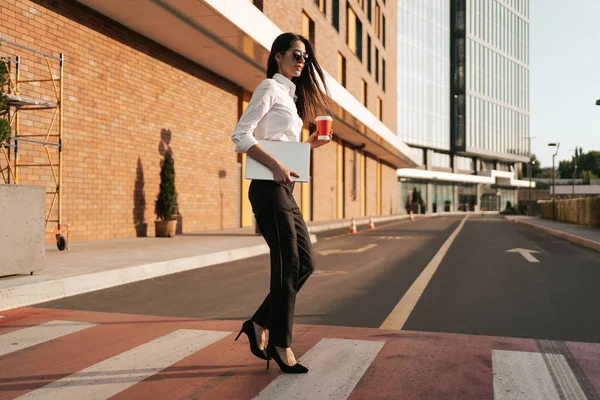 Mulher de camisa branca segurando um café para atravessar a rua — Fotografia de Stock