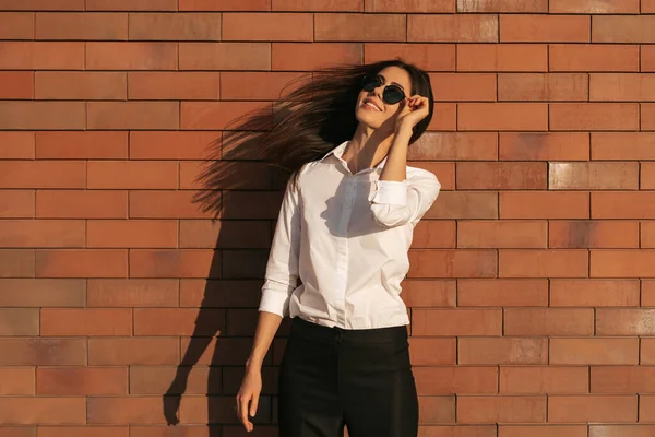 Jovem mulher retrato no fundo de tijolo em óculos de sol — Fotografia de Stock