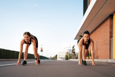 Kadın koşucular koşmaya ve birbirleriyle yarışmaya hazır.