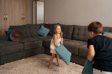 Erkek ve kız kardeş yastıklarla oynuyor.