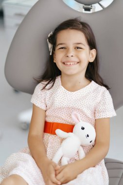 Dişçi koltuğunda gülümseyen tatlı kız.