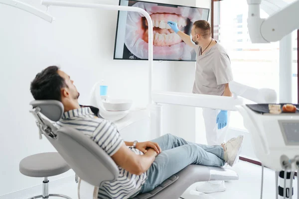 Dentista explicando a imagem dos dentes na tela — Fotografia de Stock