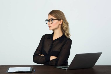 beyaz zemin üzerinde bir dizüstü bilgisayar ile masada oturan gözlüklü güzel genç kız