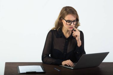 beyaz zemin üzerinde bir dizüstü bilgisayar ile masada oturan gözlüklü güzel genç kız