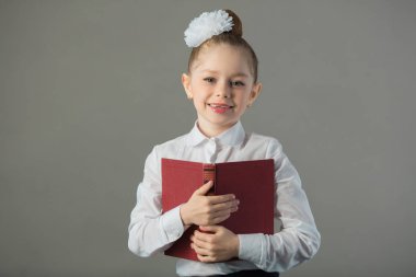 güzel genç kız bir kitapta bir masada oturan bir yay ile gri bir arka plan üzerinde eller