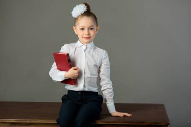 güzel genç kız bir kitapta bir masada oturan bir yay ile gri bir arka plan üzerinde eller
