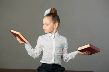 güzel genç kız bir kitapta bir masada oturan bir yay ile gri bir arka plan üzerinde eller