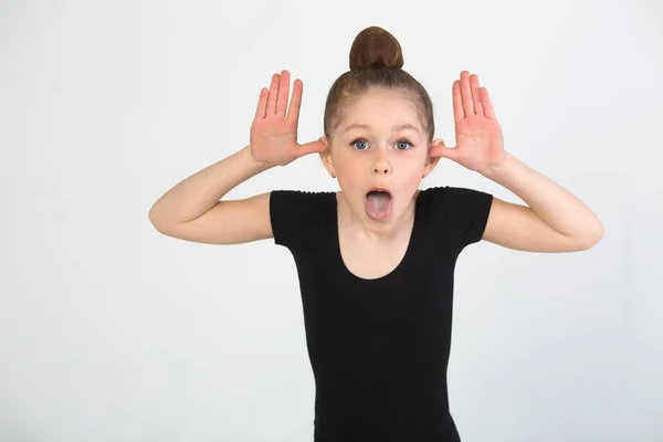 Beyaz arka planda siyah bir takım elbise içinde jimnastik yapan güzel genç kız