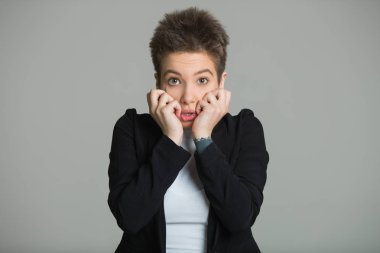 Genç güzel kız ile bir kısa saç kesimi korkmuş bir ifade ile gri bir arka plan üzerinde siyah ceket