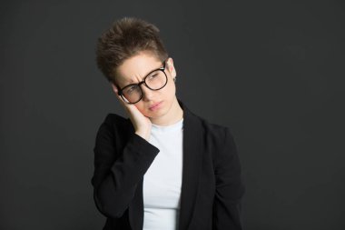 siyah bir takım elbise ve gözlük yorgun bir ifade ile siyah bir zemin üzerine kısa saçlı güzel genç kız