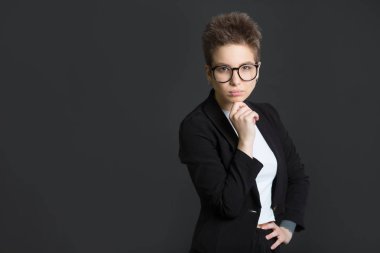 siyah bir takım elbise ve gözlük ciddi bir yüz siyah bir zemin üzerine kısa saçlı güzel genç kız