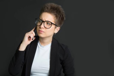 siyah bir takım elbise ve gözlük bir telefon onun elinde siyah bir zemin üzerine kısa saçlı güzel genç kız
