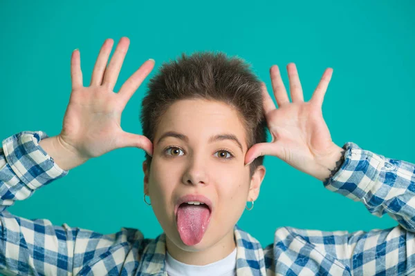 eğlenceli bir ile mavi bir arka plan üzerinde bir gömlek kısa saçlı güzel genç kız yüzünde yüz ifadesi