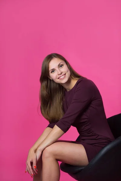 Krásná Mladá Dívka Úsměvem Tváři Tekoucí Vlasy Růžovém Pozadí Sedí — Stock fotografie