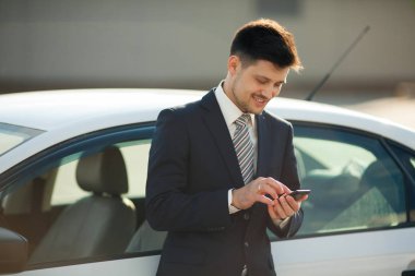 yakışıklı genç takım car yakınındaki elinde telefon ile