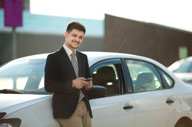 yakışıklı genç takım car yakınındaki elinde telefon ile