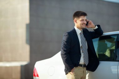 telefonda sokakta araba yakınındaki bir uymak yakışıklı genç adam