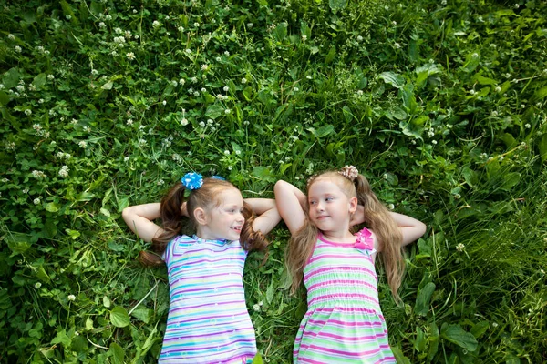 夏日公园里有两个美丽的小女孩躺在青草上 — 图库照片