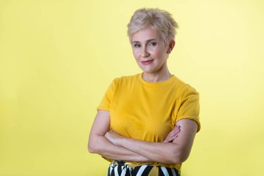 güzel şık yaşlı kadın sarı T-shirt sarı bir arka plan üzerine kısa bir saç modeli ile