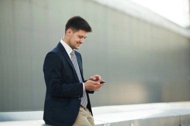 yakışıklı genç adam onun elinde bir telefon ile sokakta yaz aylarında arıyor takım elbiseli